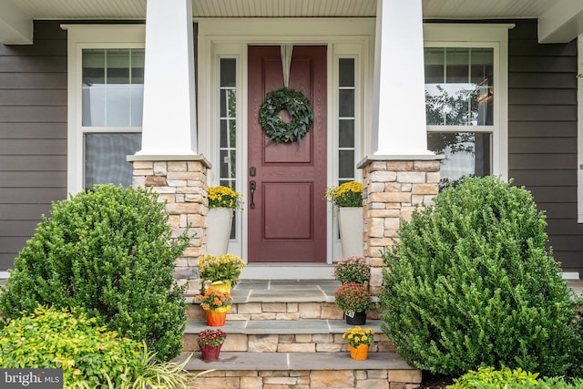 view of exterior entry with stone siding and a porch