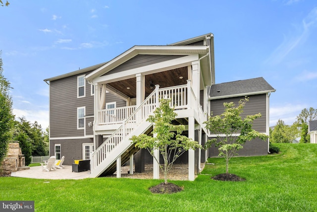 rear view of house featuring stairs, a lawn, and a patio