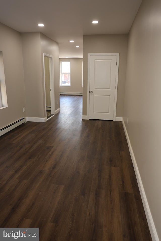 interior space with recessed lighting, a baseboard heating unit, baseboards, and dark wood-style floors