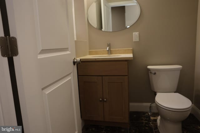 bathroom with vanity, toilet, and baseboards