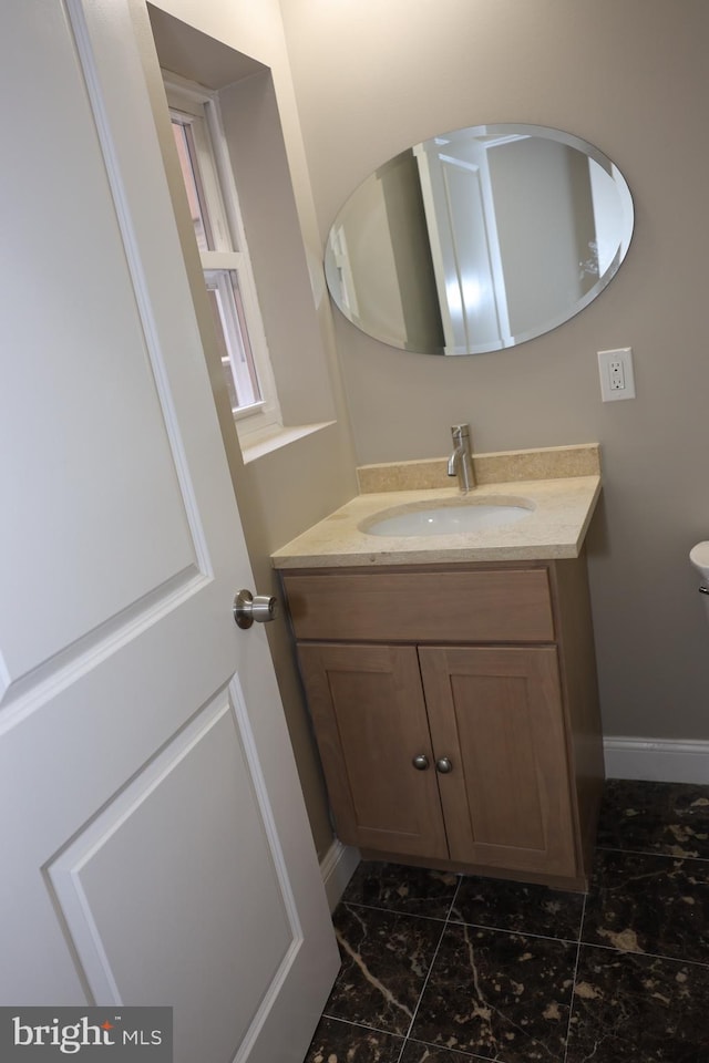 half bathroom featuring baseboards, toilet, and vanity