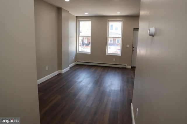 empty room with a baseboard heating unit, recessed lighting, dark wood finished floors, and baseboards