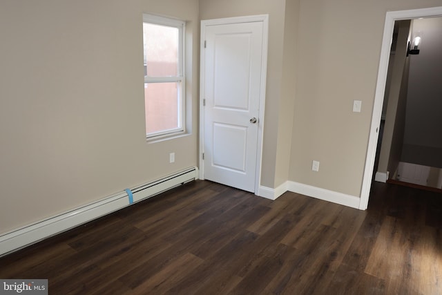 empty room featuring dark wood-style flooring, a healthy amount of sunlight, baseboards, and a baseboard radiator