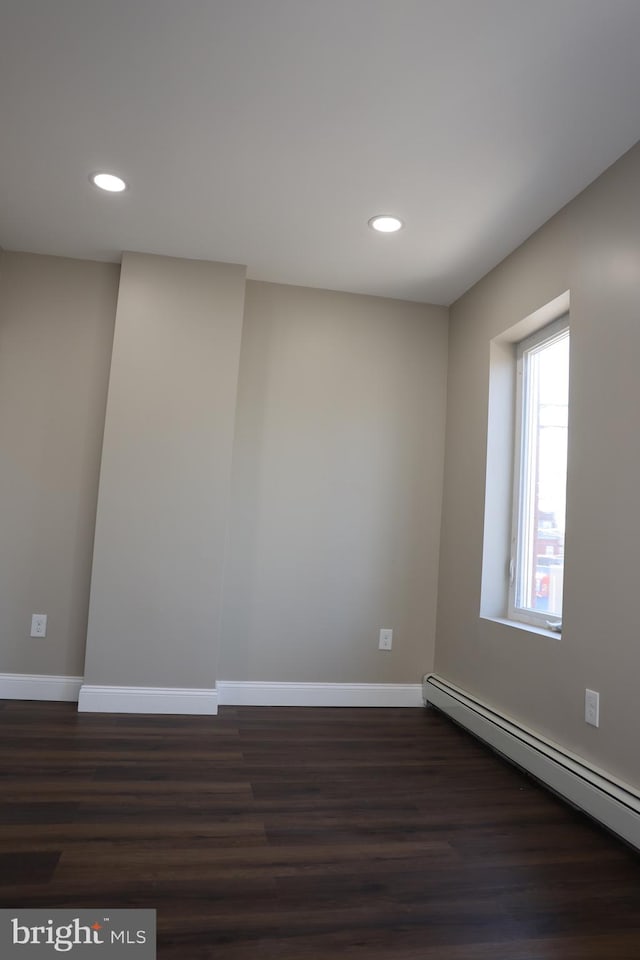 unfurnished room featuring dark wood-style floors, baseboards, and baseboard heating