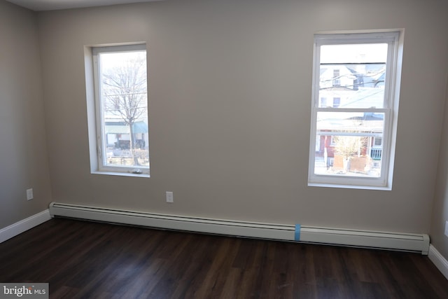 spare room featuring baseboards, baseboard heating, and dark wood finished floors