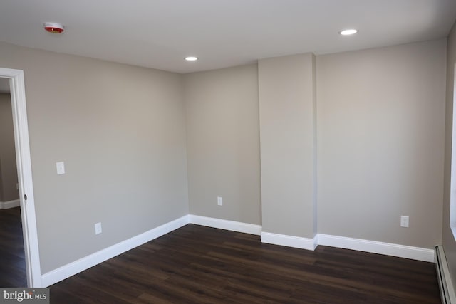 spare room with a baseboard heating unit, recessed lighting, baseboards, and dark wood-style flooring