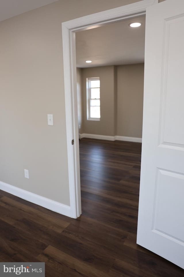 empty room with dark wood finished floors, recessed lighting, and baseboards