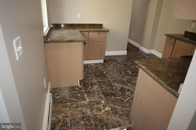 kitchen featuring a baseboard heating unit, light brown cabinets, and baseboards