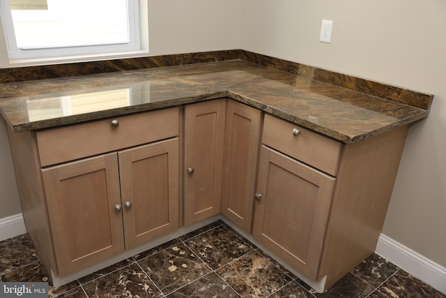 kitchen with dark stone counters, baseboards, and marble finish floor