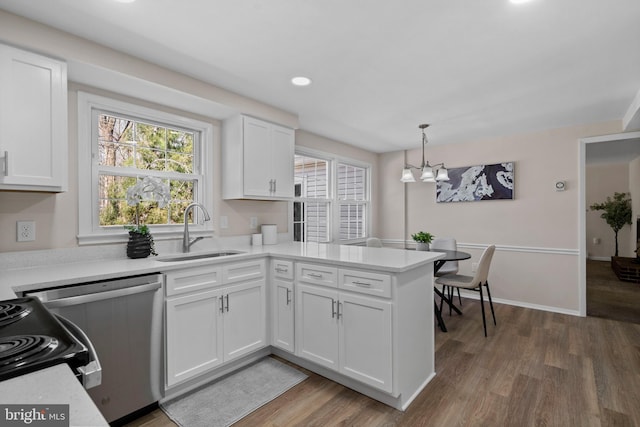 kitchen with a peninsula, white cabinets, a sink, and wood finished floors