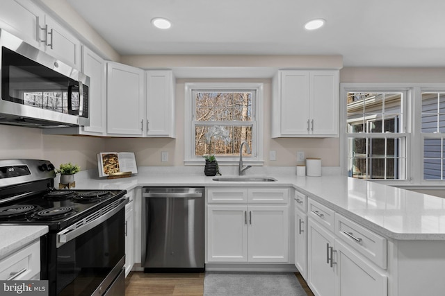 kitchen featuring white cabinets, stainless steel appliances, a sink, and recessed lighting