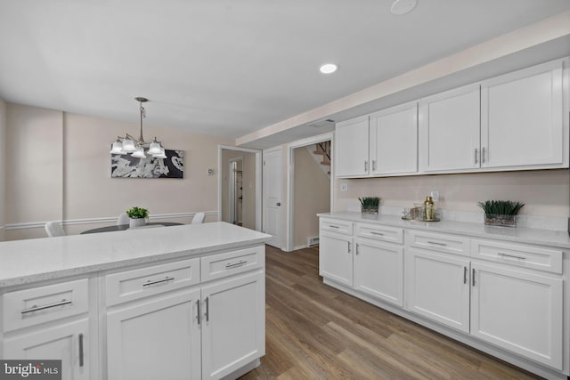 kitchen with light stone counters, wood finished floors, decorative light fixtures, white cabinetry, and recessed lighting