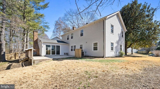 rear view of property featuring a patio area, a chimney, and a yard