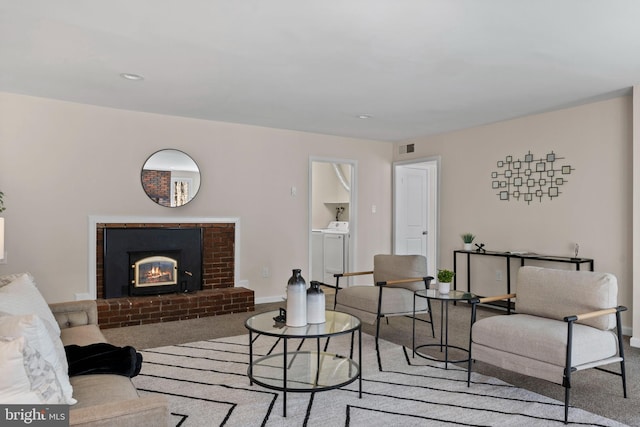 carpeted living area with baseboards, a fireplace, visible vents, and separate washer and dryer