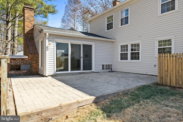 rear view of property featuring a patio, a chimney, and fence