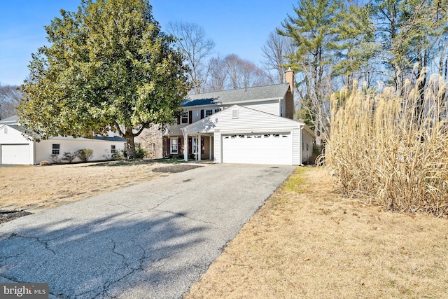 view of front of property featuring a garage, driveway, and a chimney