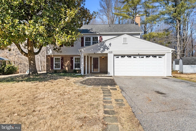 colonial home featuring an attached garage, brick siding, driveway, a front lawn, and a chimney