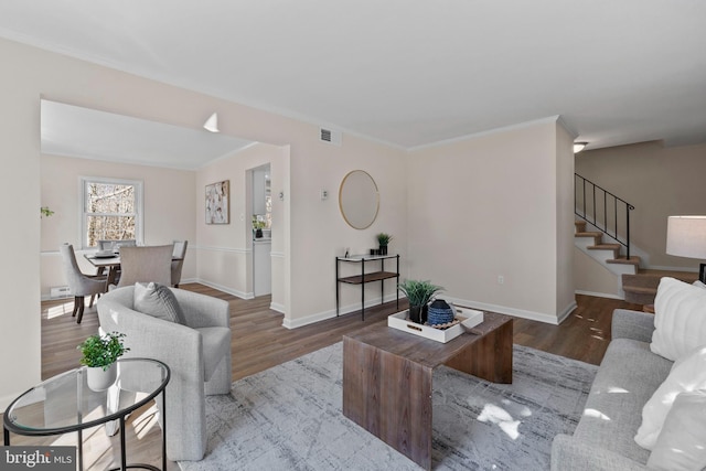 living room with wood finished floors, visible vents, baseboards, stairs, and ornamental molding