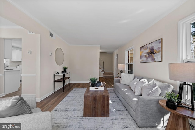 living room with crown molding, visible vents, stairway, wood finished floors, and baseboards