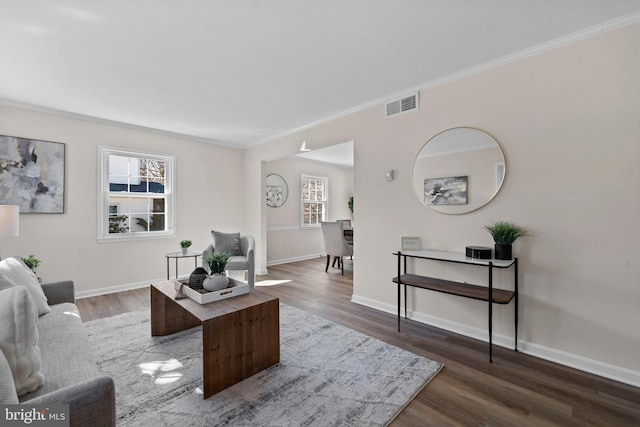 living room with visible vents, crown molding, baseboards, and wood finished floors