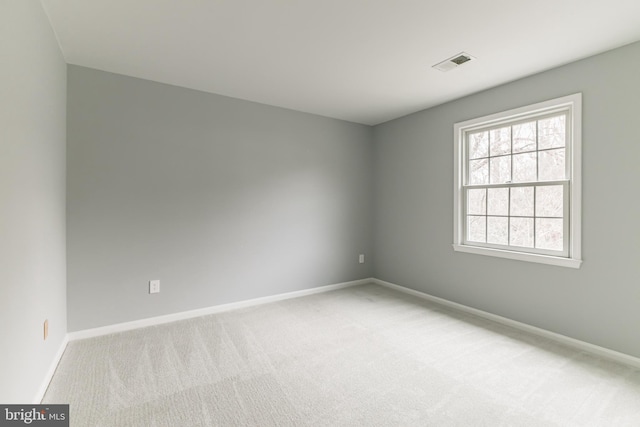 empty room featuring light carpet, visible vents, and baseboards