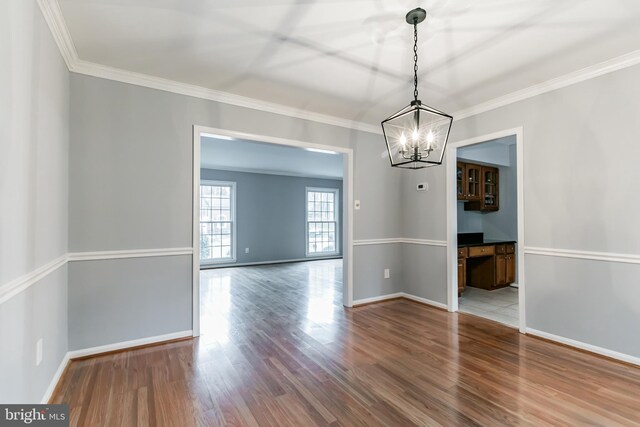 unfurnished dining area featuring ornamental molding, baseboards, and wood finished floors