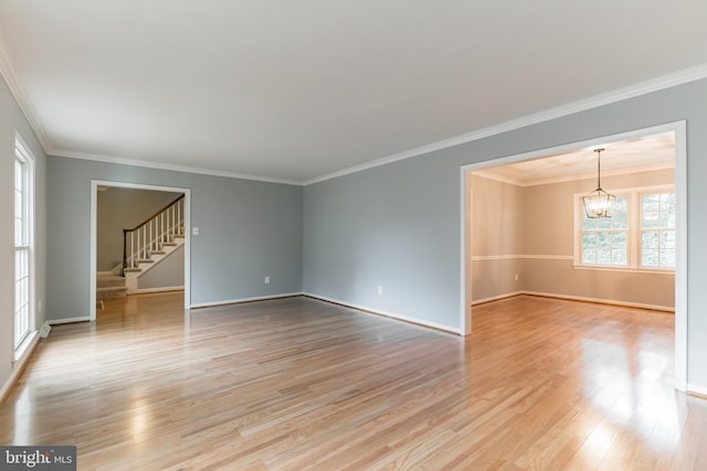 empty room with baseboards, stairs, crown molding, light wood-style floors, and a chandelier