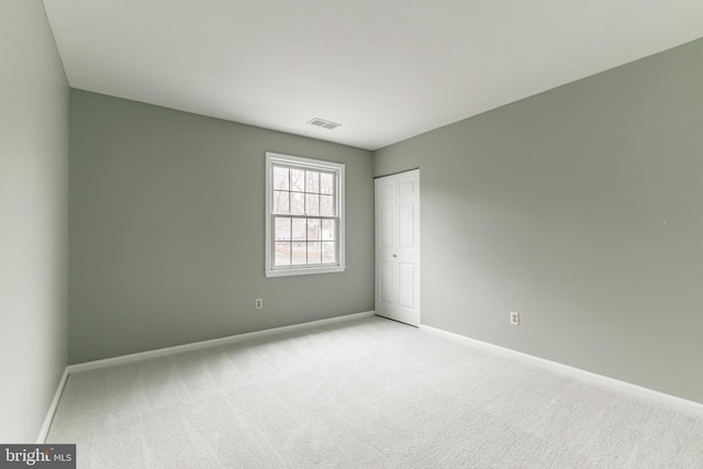 unfurnished room with light carpet, visible vents, and baseboards