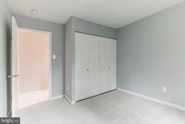 unfurnished bedroom with carpet floors, baseboards, and a closet