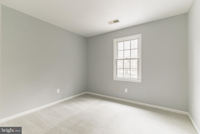 spare room featuring baseboards, visible vents, and light colored carpet