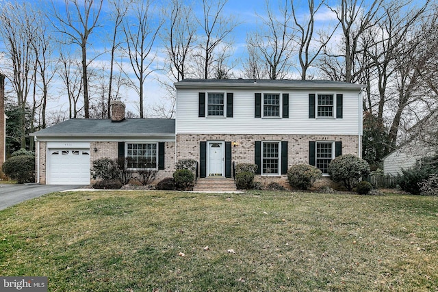 colonial house with a garage, a chimney, aphalt driveway, a front lawn, and brick siding