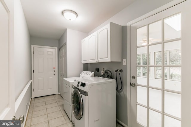 clothes washing area featuring light tile patterned floors, washing machine and dryer, and cabinet space