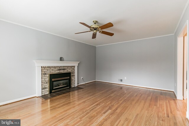 unfurnished living room featuring a brick fireplace, a ceiling fan, ornamental molding, and wood finished floors