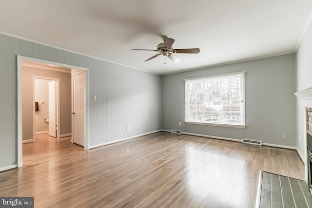 unfurnished living room with a ceiling fan, visible vents, wood finished floors, and ornamental molding