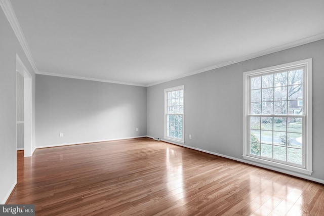 unfurnished room featuring baseboards, wood finished floors, visible vents, and crown molding