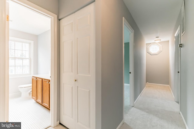 corridor featuring light colored carpet and baseboards