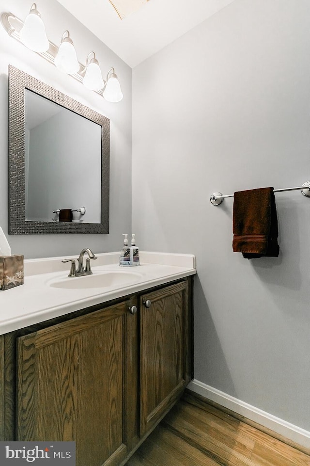 bathroom featuring baseboards, wood finished floors, and vanity