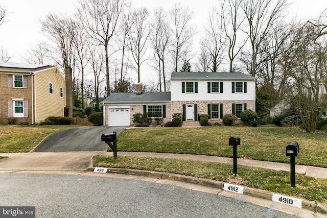 view of front of home featuring driveway, brick siding, an attached garage, and a front yard