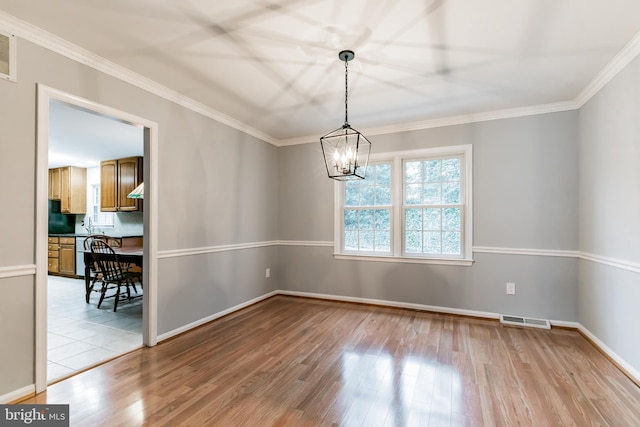 empty room featuring visible vents, crown molding, and light wood finished floors