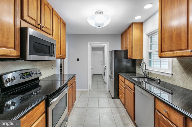 kitchen with light tile patterned floors, baseboards, brown cabinets, stainless steel appliances, and a sink