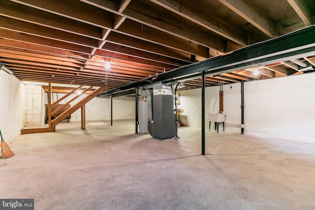 unfinished basement with water heater, a sink, and heating unit