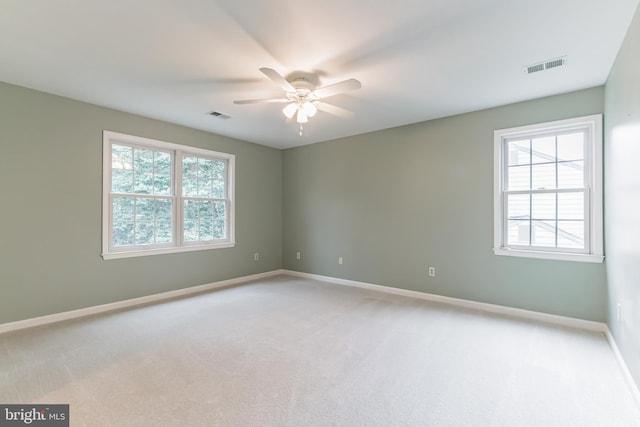 spare room featuring a healthy amount of sunlight, baseboards, visible vents, and light colored carpet