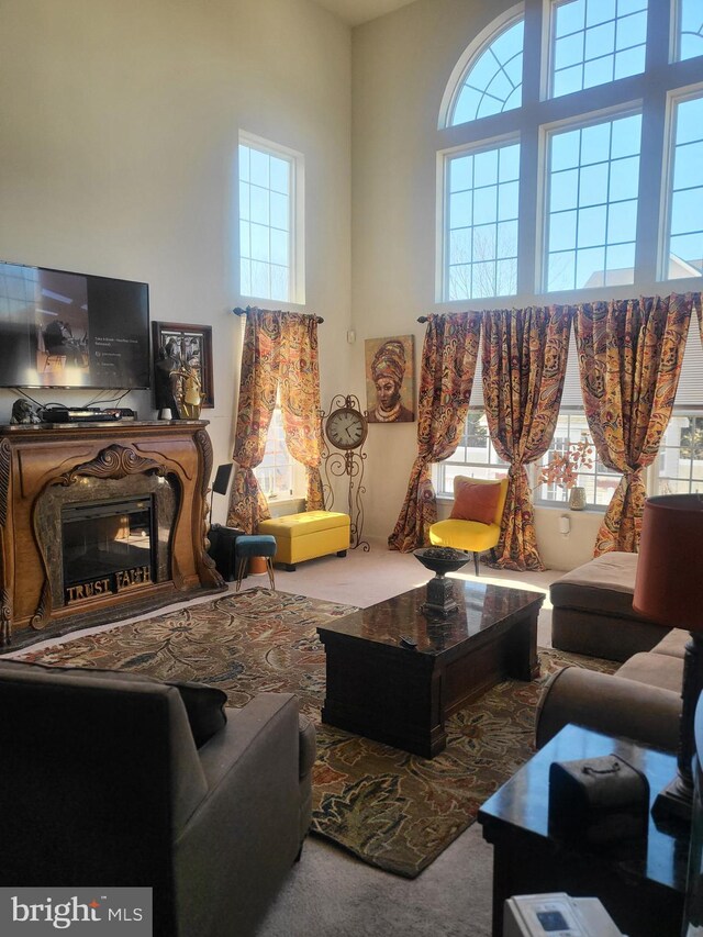 living area with carpet flooring, a high ceiling, plenty of natural light, and a fireplace