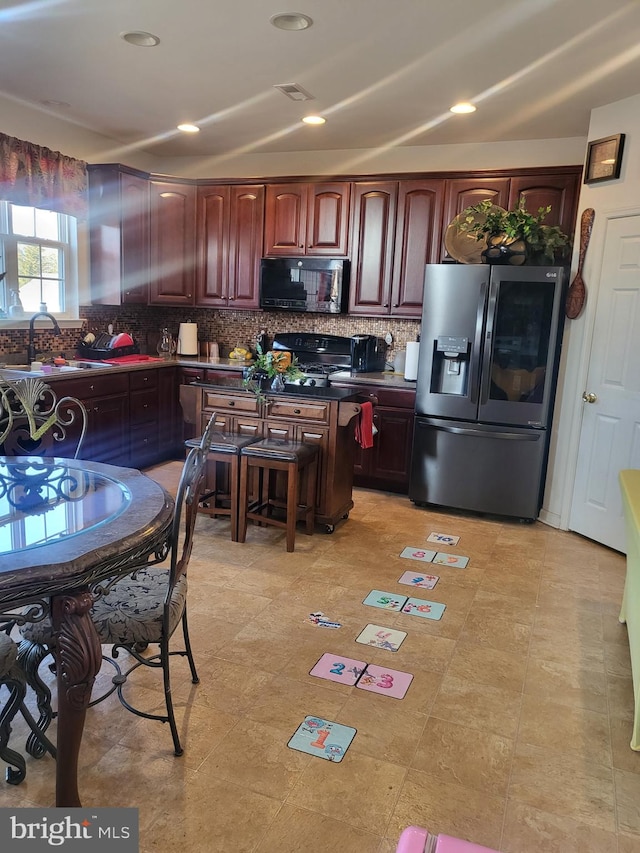 kitchen featuring stainless steel fridge with ice dispenser, tasteful backsplash, black microwave, and a sink