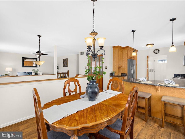 dining space with visible vents, ceiling fan with notable chandelier, and wood finished floors