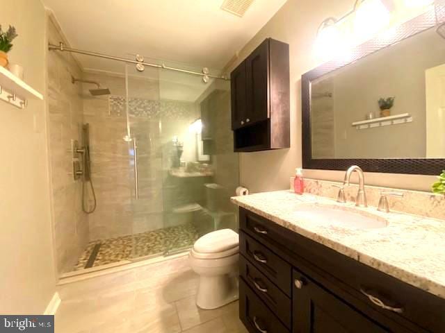 full bathroom featuring visible vents, a stall shower, toilet, and vanity