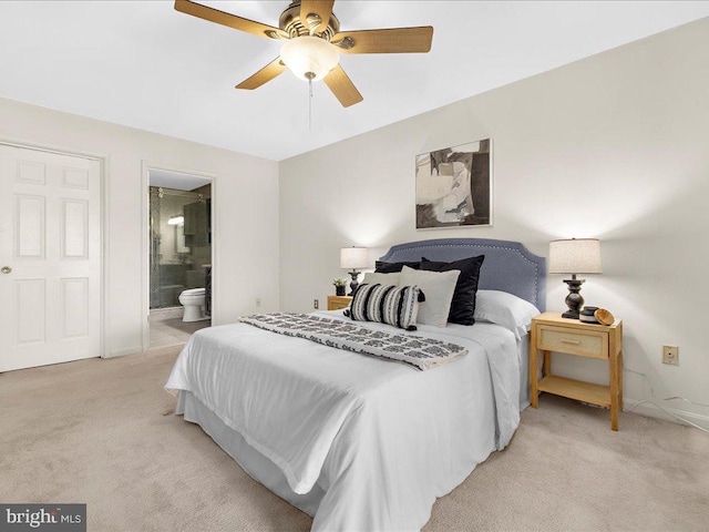 bedroom featuring light colored carpet, a ceiling fan, ensuite bathroom, and baseboards