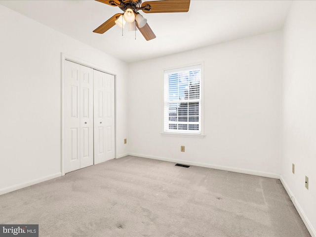 unfurnished bedroom featuring visible vents, a ceiling fan, a closet, carpet, and baseboards