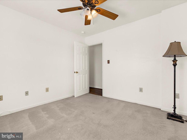 unfurnished room with ceiling fan, baseboards, and light carpet