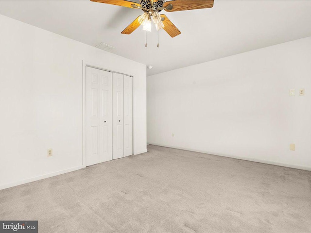 unfurnished bedroom featuring a closet, carpet flooring, baseboards, and a ceiling fan